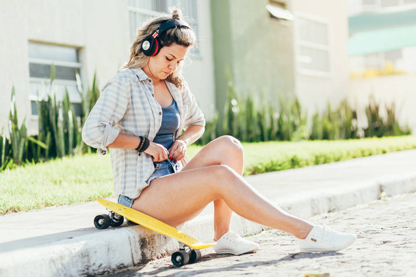Portrait of beautiful woman with skateboard in the city. - Фото, изображение