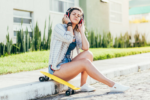 Portrait of beautiful woman with skateboard in the city. - Фото, изображение
