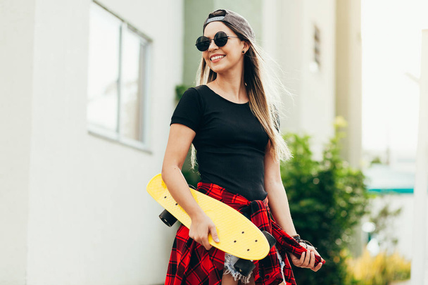Portrait of smiling young female skateboarder with her skateboar - Zdjęcie, obraz