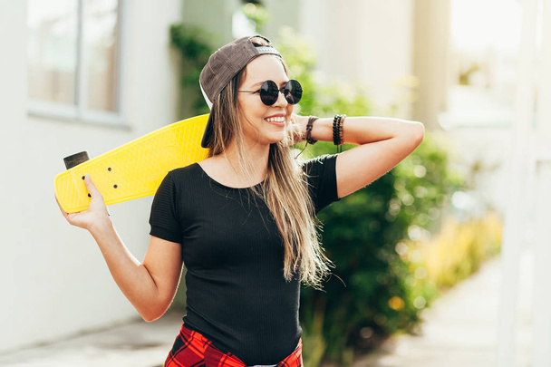 Portrait of smiling young female skateboarder with her skateboar - Foto, afbeelding