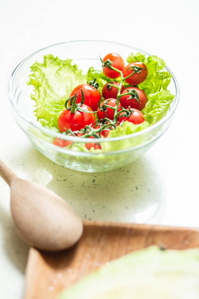 Close up of wooden spoon and bowl with fresh lettuce and cherry tomatoes in it - Fotoğraf, Görsel