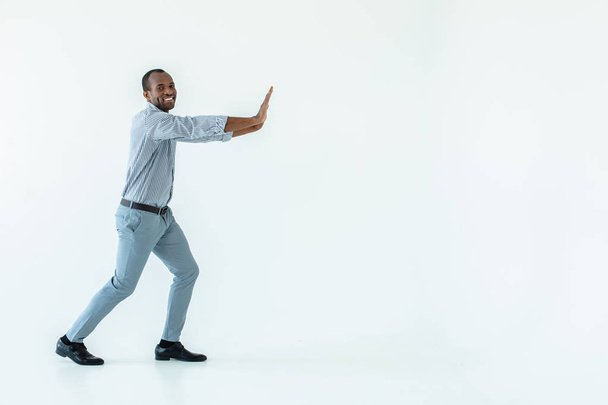 Move it. Optimistic afro american man pushing the block against white background - Photo, image