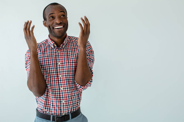 So emotional. Joyful afro american man feeling excited while standing against white background - Fotó, kép
