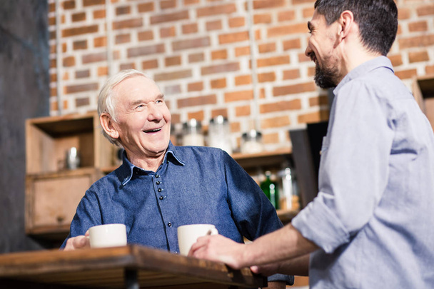 楽しいコミュニケーション。台所に立ちながら息子と話す笑顔の老人の低い角度 - 写真・画像