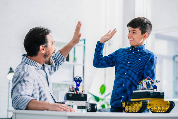 Positive father and his smart son giving high five while resting together at home - Photo, image