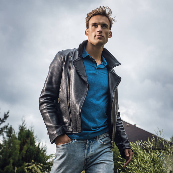 Young handsome man in classic leather jacket pose in summer garden. - Fotografie, Obrázek