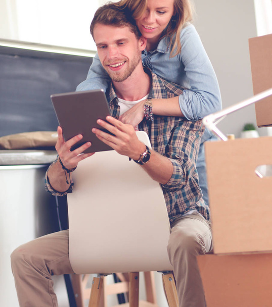 Young couple moving in new home.Sitting and relaxing after unpacking.Looking something on laptop. Young couple - Foto, Imagem