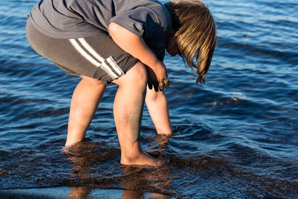 Дитина копає на пляжі у воді
 - Фото, зображення
