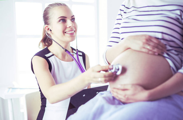 Doctora joven examinando a una mujer embarazada en la clínica. - Foto, Imagen