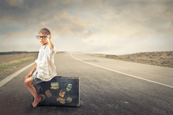 Kid waiting sitting on a suitcase - 写真・画像