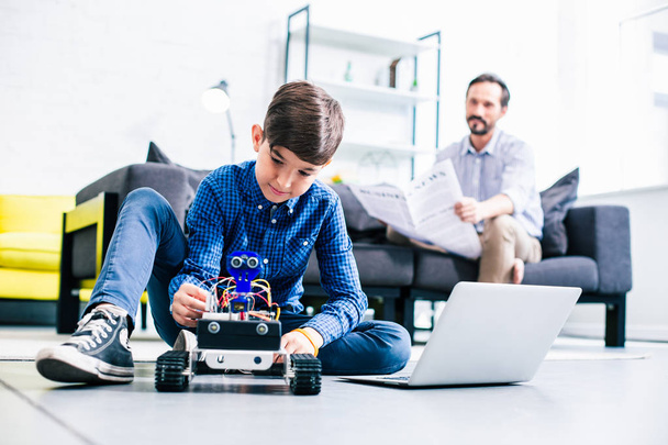 Smart delighted boy testing his robot while preparing for engineering classes - 写真・画像