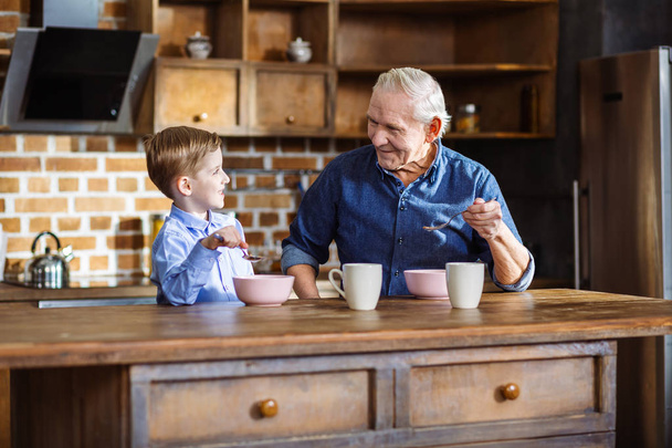 Positive son and his grandson eating cereal - 写真・画像