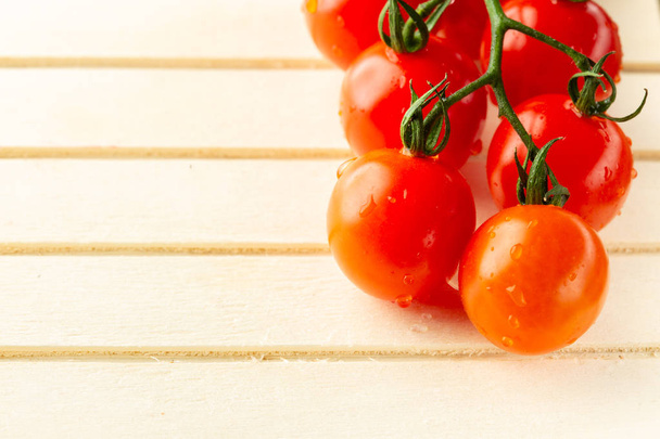 Close up photo with fresh clean branch of ripe cherry tomatoes lying on the wooden surface. Copy space on the left side - Φωτογραφία, εικόνα
