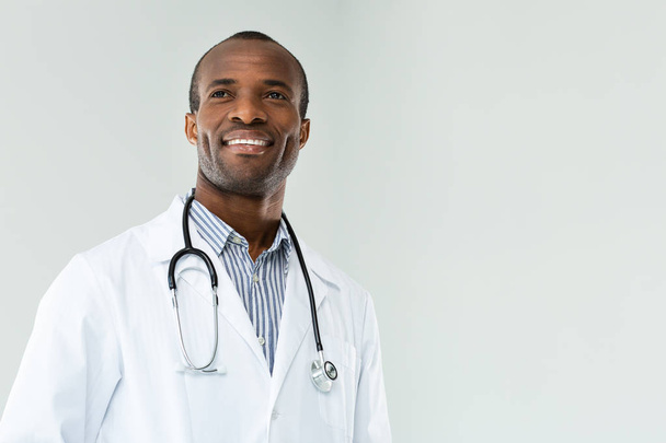 Confident in my work., Positive handsome afro american doctor smiling while standing against white background - Photo, Image