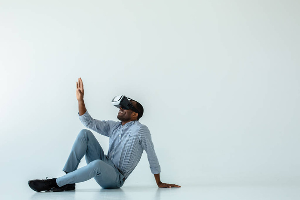 Exciting view. Cheerful afro american man sitting on the floor while testing vr glasses - Valokuva, kuva