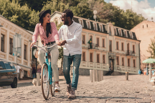 Smiling lady riding a bike down the street and boyfriend walking next to her. Template banner - Zdjęcie, obraz