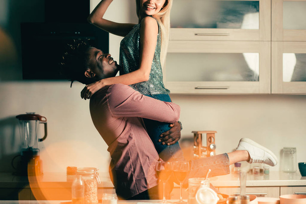 Cheerful young lady smiling while being in the arms of her beloved man - Фото, изображение