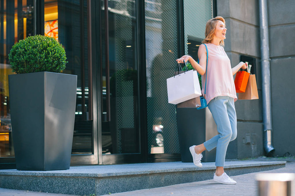 Cheerful woman feeling excited and walking out of the shop with paper bags. Website banner - Foto, imagen