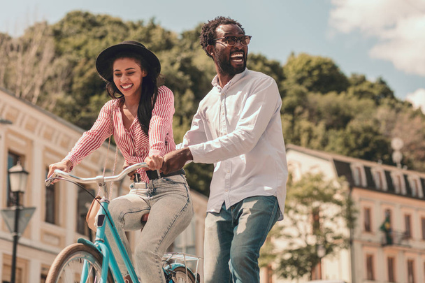 Happy man turning and smiling while smiling woman riding a bike - Fotoğraf, Görsel