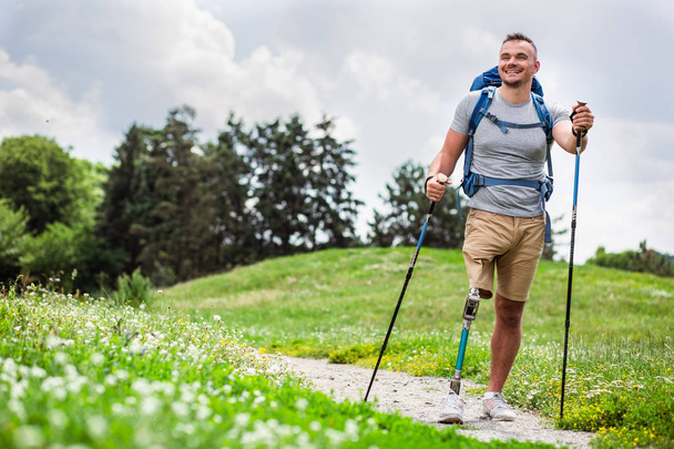 Full length of a nice positive young man with prosthesis having a walk outdoors and enjoying his hobby - Foto, immagini