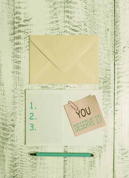 Writing note showing You Deserve It. Business photo showcasing should have it because of their qualities or actions Envelop squared notepad note clip marker old wooden vintage background. - Photo, Image