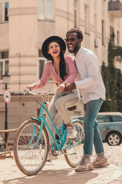 Excited young man with woman on the bike in the street - Fotó, kép