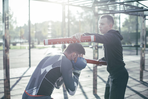 Kendine güvenen eğitmen boksörler kafasına boks sopa koyarak ve onu duruş performans yapma - Fotoğraf, Görsel