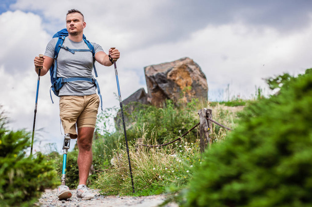 Young confident man with prosthesis trying Nordic walking while spending time outdoors - Фото, зображення
