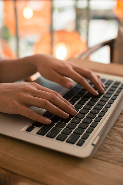 Close up photo of a modern laptop and woman putting both hands on the keyboard while using it - Foto, afbeelding