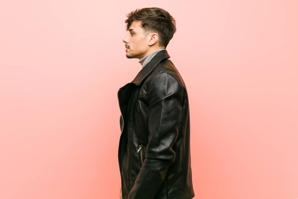 Jovem hispânico vestindo uma jaqueta de couro olhando para a esquerda, pose lateral
. - Foto, Imagem