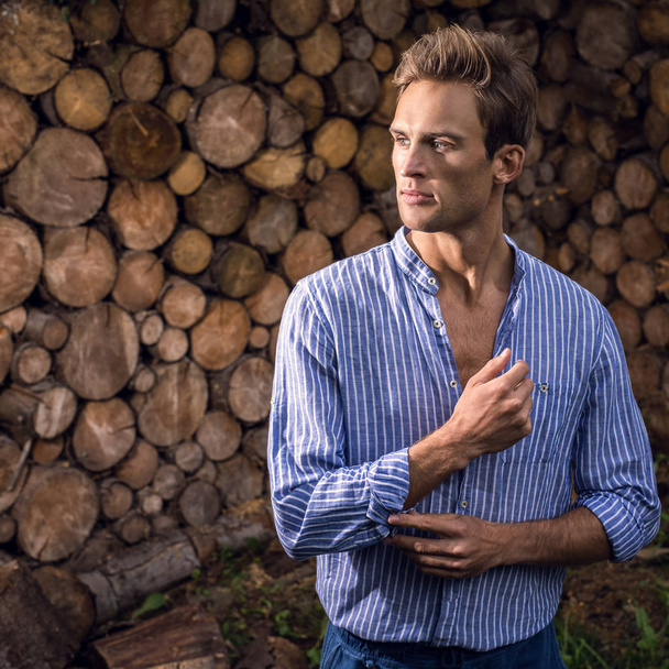 Young handsome man in casual shirt poses near wooden background. - Fotó, kép