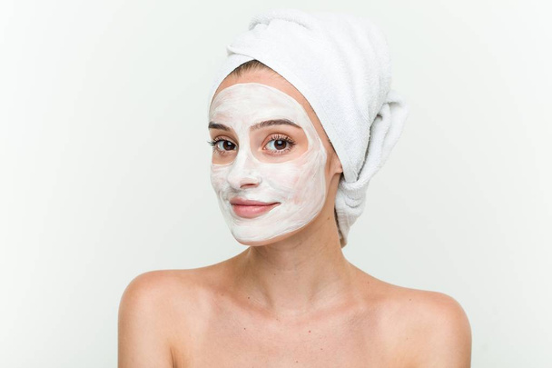 Young caucasian woman enjoying of a facial mask treatment - Foto, imagen