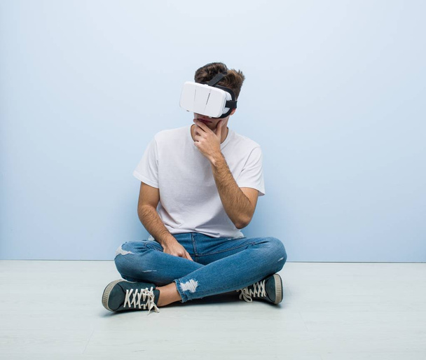 Teenager caucasian man using a virtual reality glasses sitting on the floor - Valokuva, kuva
