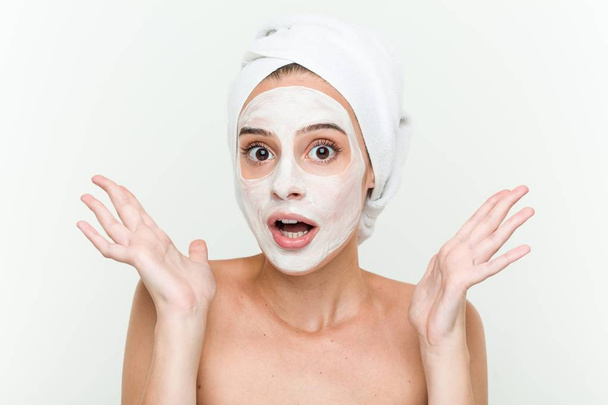 Young caucasian woman enjoying of a facial mask treatment - Zdjęcie, obraz