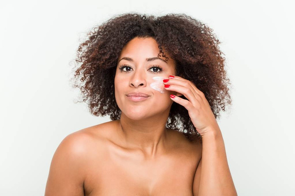 Gros plan d'une jeune femme afro-américaine appliquant une crème hydratante
 - Photo, image