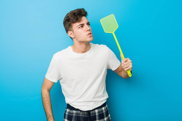 Έφηβος Καυκάσιος άντρας που φοράει πιτζάμες και κρατάει ένα φλαουγουάτερ - Φωτογραφία, εικόνα