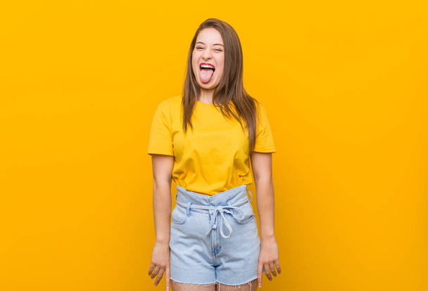 junge Frau Teenager trägt ein gelbes Hemd lustig und freundlich herausstreckende Zunge. - Foto, Bild