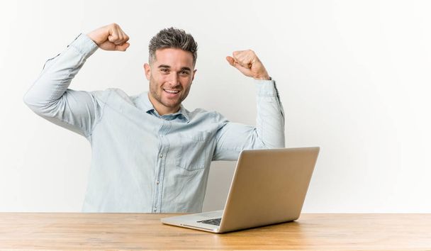 Fiatal csinos férfi dolgozik az ő laptop mutató erőt gesztus karokkal, jelképe feminin hatalom - Fotó, kép