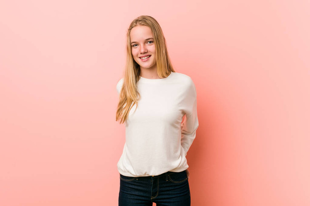 Caucasian teenager standing against a pink background - Фото, зображення