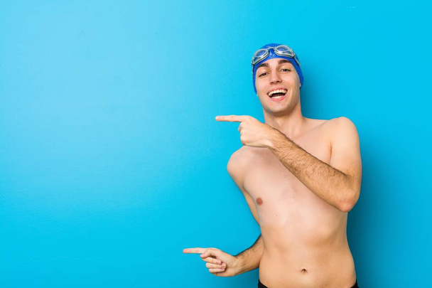 Jonge zwemmer man opgewonden wijzend met controller weg. - Foto, afbeelding