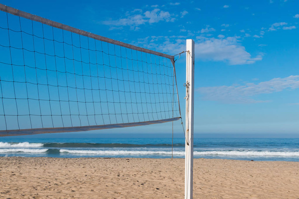 Rede de vôlei em um campo de areia de praia com o oceano no fundo
. - Foto, Imagem