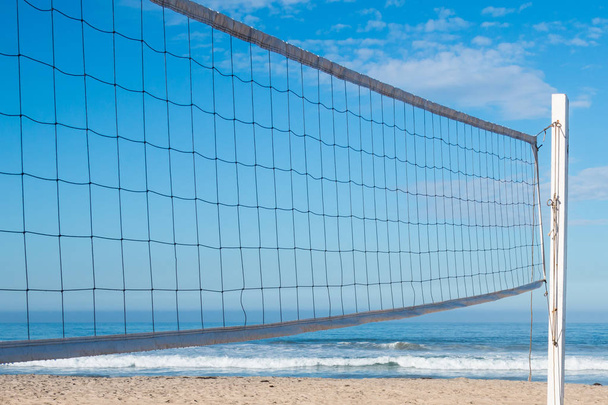 Beach volleyball net with ocean waves in the background. - Photo, Image