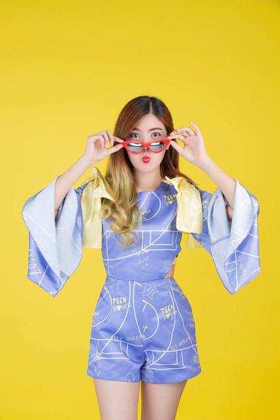 Fashion girl dress up with a hand gesture on a yellow background. - Photo, Image