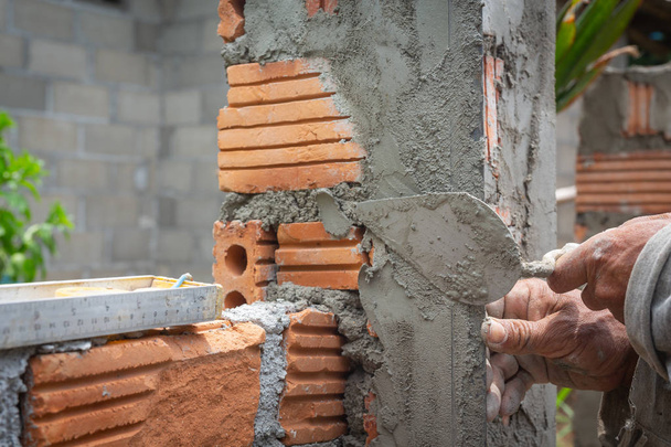 Colocação de tijolos. Trabalhador da construção civil construindo uma parede de tijolo
. - Foto, Imagem