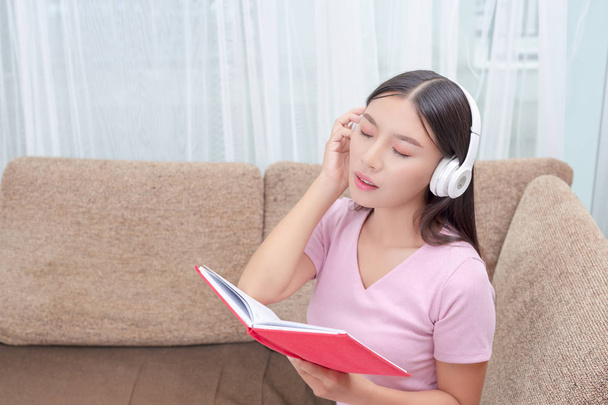 Girl lying on the couch listening to music and reading books. - Foto, Bild