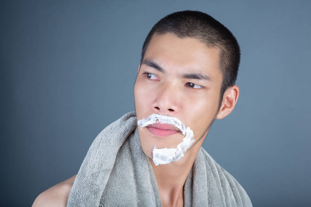 Shaving handsome guy shaved on the face on a gray background. - Zdjęcie, obraz