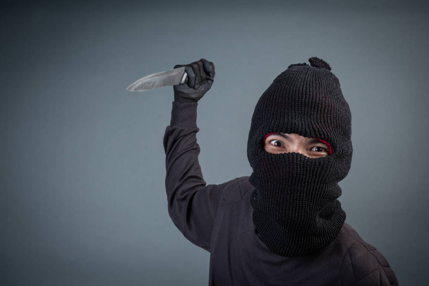 Criminals wear black mask and hold dark on gray background. - Photo, Image