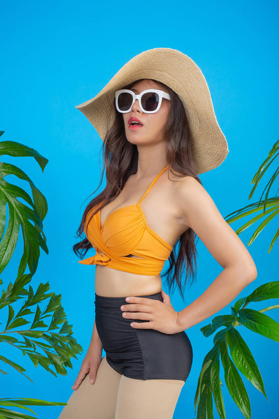 Beautiful woman in a swimsuit poses a gesture on a blue background. - Photo, Image