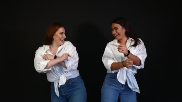 Meisjes in witte shirts dansen en gek rond op een zwarte achtergrond - Video