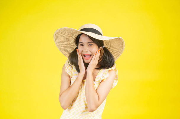 A beautiful, happy woman wearing a big hat showing cheerfulness on a yellow background. - Foto, imagen